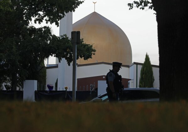 
              FILE - In this March 17, 2019, file photo, a police officer stands guard in front of the Al Noor mosque in Christchurch, New Zealand. On Friday, the imam, Gamal Fouda, had just finished the Khutbah, the formal sermon that’s delivered in Arabic, and he had started the next part in which he translated it into English. As the gunman approached the mosque, a man in the entrance called out cheerfully, “Hello, brother.” Brenton Tarrant fired several shots, one after another, and walked past the first bodies.(AP Photo/Vincent Yu, File)
            