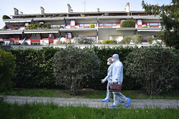 Medical staffers wearing protective gear, part of a special unit performing house calls, walk in Bergamo, northern Italy, one of the areas worse-affected by coronavirus, Wednesday, March 25, 2020. The new coronavirus causes mild or moderate symptoms for most people, but for some, especially older adults and people with existing health problems, it can cause more severe illness or death. (Claudio Furlan/LaPresse via AP)