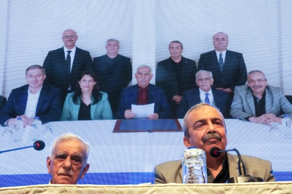 Pro-Kurdish Peoples' Equality and Democracy Party, or DEM, delegation members release an statement from the jailed leader of the rebel Kurdistan Workers' Party, or PKK, Abdullah Ocalan, center at the background photo, in Istanbul, Turkey, Thursday, Feb. 27, 2025. (AP Photo/Khalil Hamra, File)
