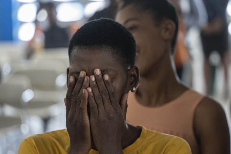 A woman covers her face as part of an exercise during a class for adults on how to help children overcome trauma and fear amid violence, in Port-au-Prince, Haiti, Sunday, May 5, 2024. As young Haitians are increasingly exposed to violence, the country is undergoing a wider push to dispel a long-standing taboo on seeking therapy and talking about mental health. (AP Photo/Ramon Espinosa)