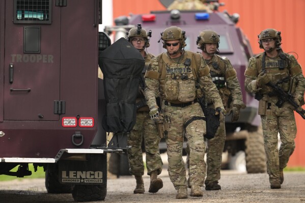 Members of law enforcement agencies search for shooting suspect, Vance Boelter, at a house Sunday, June 15, 2025, in Belle Plaine, Minn. (AP Photo/George Walker IV)