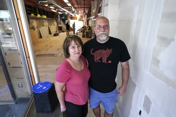 Bear Pond Books owners Claire Benedict, left, and Rob Kasow, pose in their shop, which is being rebuilt following the July flooding, Tuesday, Aug. 1, 2023, in Montpelier, Vt. (AP Photo/Charles Krupa)