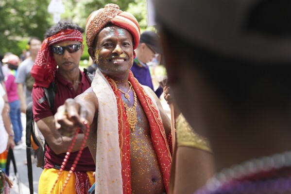 Anand Ramphal, of Silver Spring, Md., hands out beads during the World Pride parade, Saturday, June 7, 2025, in Washington. (AP Photo/Jacquelyn Martin)