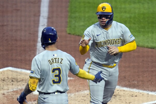 Milwaukee Brewers' William Contreras is greeted by Joey Ortiz (3) after scoring on a bases load walk issued by Pittsburgh Pirates relief pitcher Luis L. Ortiz to Brewer's Blake Perkins during the third inning of a baseball game in Pittsburgh, Wednesday, April 24, 2024. (AP Photo/Gene J. Puskar)