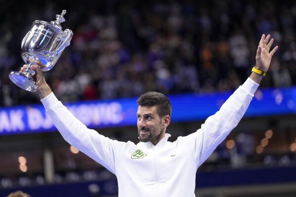 Novak Djokovic, of Serbia, holds up the championship trophy after defeating Daniil Medvedev, of Russia, in the men's singles final of the U.S. Open tennis championships, Sunday, Sept. 10, 2023, in New York. (AP Photo/Manu Fernandez)