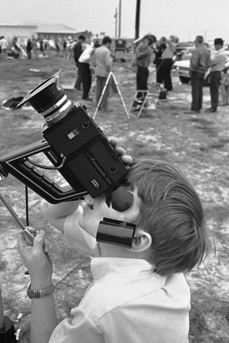 FILE - Steve Spalding of Chattanooga squints through the viewfinder of a movie camera for the sun at a Valdosta industrial park as the solar eclipse began in Valdosta, Ga., on Saturday, March 7, 1970. The search was in vain, however, as the sun remained hidden behind a heavy cloud cover before hiding behind the moon. In background, many of the amateur astronomers who traveled to see the total eclipse from as far as western Canada stand disappointedly beside idle telescopes. (AP Photo/Joe Holloway Jr., File)