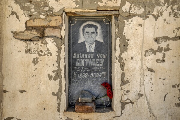 A man's photo is visible on his grave in a cemetery near the dried-up Aral Sea, on the outskirts of Muynak, Uzbekistan, Monday, June 26, 2023. (AP Photo/Ebrahim Noroozi)