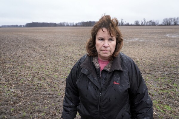 Clara Ostrander stands in her family's field in Maybee, Mich., Tuesday, Jan. 9, 2024. The family sought to lease some of the property for a solar energy project that would have paid enough to help them keep their land. Local opposition tanked the project and Ostrander now says there are neighbors she will never speak to again. (AP Photo/Paul Sancya)