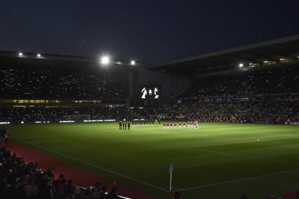 Players stand on the center of the pitch during a moment of silence tribute to Queen Elizabeth II before the English Premier League soccer match between Aston Villa and Southampton at Villa Park in Birmingham, England, Friday, Sept. 16, 2022. (AP Photo/Rui Vieira)