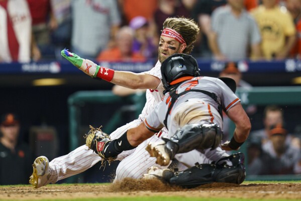 Philadelphia Phillies' Bryce Harper, top, is tagged out by Baltimore Orioles' James McCann, bottom, during the eighth inning of a baseball game, Monday, July 24, 2023, in Philadelphia. (AP Photo/Chris Szagola)