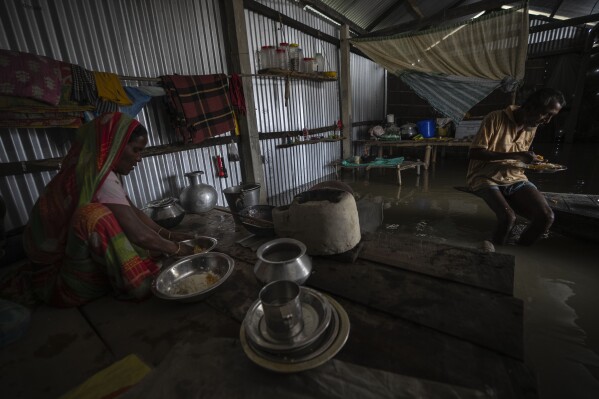 Yaad Ali, 55, right, and his wife Monuwara Begum, 45, eat a meal in their submerged house in Sandahkhaiti, a floating island village in the Brahmaputra River in Morigaon district, Assam, India, Wednesday, Aug. 30, 2023. (APPhoto/Anupam Nath)