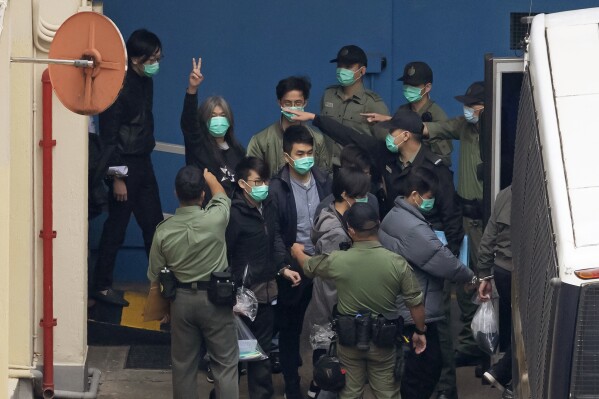 FILE - Former lawmaker Leung Kwok-hung, known as "Long Hair," second left, shows a victory sign as some of the 47 pro-democracy activists are escorted by Correctional Services officers to a prison van in Hong Kong, Thursday, March 4, 2021. Verdicts in Hong Kong’s largest national security case to date will be delivered on Thursday, May 30, 2024. (AP Photo/Kin Cheung, File)