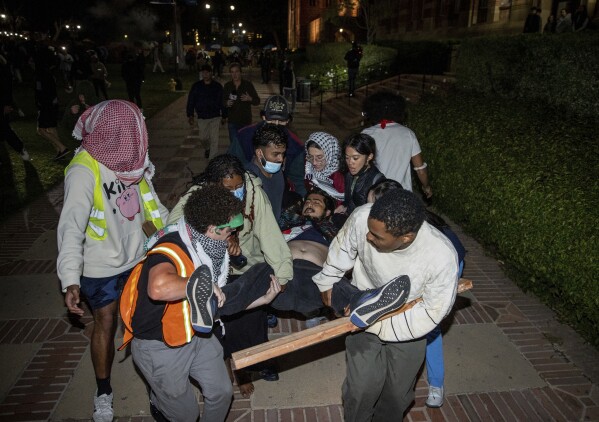A person is carried away as counter-demonstrators confront a pro-Palestinian encampment at UCLA Tuesday, April 30, 2024, in Los Angeles. Violence erupted as protests sweep across college campuses in America. (AP Photo/Ethan Swope)