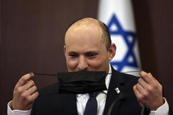 Israeli Prime Minister Naftali Bennett adjusts his mask during a cabinet meeting at the Prime Minister's office in Jerusalem, Sunday, Nov. 28, 2021. (Ronen Zvulun/Pool via AP)