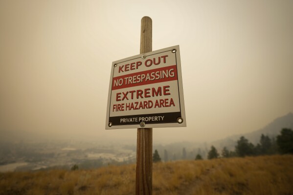 A warning sign about fire risk is seen as smoke from wildfires fills the air, in Kelowna, British Columbia, Saturday, Aug. 19, 2023. (Darryl Dyck/The Canadian Press via AP)