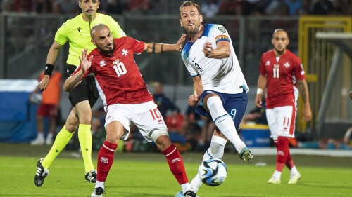 England's Harry Kane, right, challenges for the ball with Malta's Teddy Teuma during the Euro 2024 group C qualifying soccer match between Malta and England at the National stadium in Ta' Qali, near Valletta, Malta, Friday, June 16, 2023. (AP Photo/Rene Rossignaud)