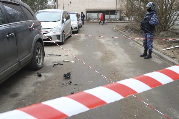 A police officer guards an area with the wreckage of a drone near a damaged apartment's building after a reported drone attack in St. Petersburg, Russia, Saturday, March 2, 2024. Russian authorities said Saturday morning that an 