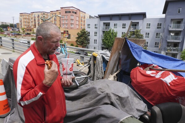 Scott Robertson Serge eats lunch in a homeless encampment where he currently lives, Monday, May 12, 2025, in Los Angeles. (AP Photo/Damian Dovarganes)