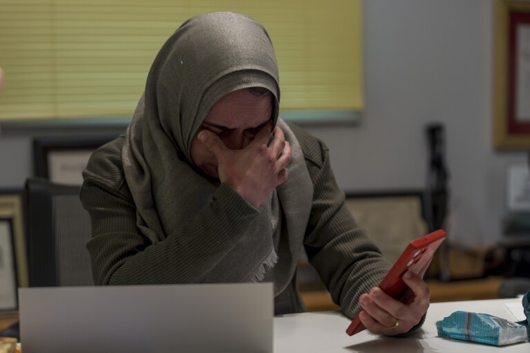 Maha Abu Kuwaik, from Gaza, sheds tears at the Global Medical Relief Fund residence while viewing images on her phone of her deceased relatives, casualties of Israeli airstrikes, Tuesday, Jan. 30, 2024, in the Staten Island borough of New York. (AP Photo/Peter K. Afriyie)