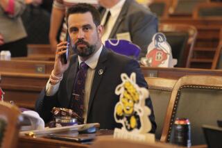 In this photo from Monday, May 3, 2021, Kansas state Rep. Mark Samsel, R-Wellsville, talks on his cellphone ahead of the House's daily session, at the Statehouse in Topeka, Kan. Samsel has been charged with three counts of misdemeanor battery over incidents involving two teenage students while he was substitute teaching. (AP Photo/John Hanna)