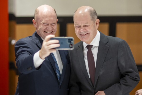 In this photo provided by Bundesregierung, from left, Sen. Chris Coons, D-Del., and German Chancellor Olaf Scholz pose for a selfie on X, formerly Twitter, on Feb. 8, 2024. Both were seeing double when they met in Washington, D.C., this week and went on social media to share their mirror image with the world. (Bundesregierung.de via AP)