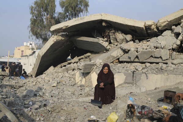 Palestynka wysiedlona w wyniku izraelskiego bombardowania w Strefie Gazy siedzi przed zniszczonym domem w Rafah, środa, 27 grudnia 2023 r.  (AP Photo/Hatem Ali)