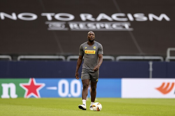 FILE - Inter Milan's Romelu Lukaku walks on the pitch in front of a 'no to racism' banner during the training session prior the Europa League round of 16 soccer match between Inter Milan and Getafe at the Veltins-Arena in Gelsenkirchen, Germany, Tuesday, Aug. 4, 2020. U.N.-backed human rights experts focusing on racial discrimination called on Italy's government to do more to eliminate acts of violence, hate speech, stigmatization and harassment against Africans and people of African descent, and expressed concern that no legal cases have been brought to punish fans and others racist acts at sports events. (Lars Baron/Pool via AP, File)