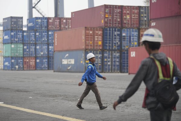 Workers walk by as shipping containers are stacked at Jakarta International Container Terminal (JICT) at Tanjung Prior Port in Jakarta, Indonesia, Friday, April 11, 2025.(AP Photo/Tatan Syuflana)