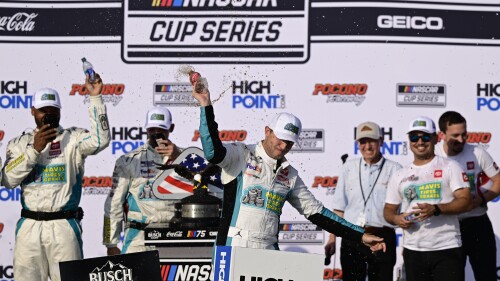 Denny Hamlin, center, celebrates in Victory Lane after winning a NASCAR Cup Series auto race at Pocono Raceway, Sunday, July 23, 2023, in Long Pond, Pa. (AP Photo/Derik Hamilton)