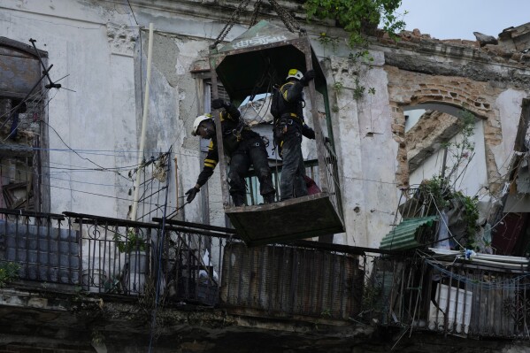Los bomberos están parados en una jaula, sostenida por una grúa, mientras buscan sobrevivientes después del colapso parcial de un edificio en La Habana, Cuba, el miércoles 4 de octubre de 2023. (AP Foto/Ramón Espinosa)