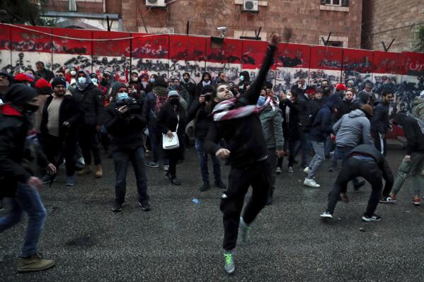 Anti-government protesters throw stones towards the central bank building during a demonstration to denounce the country's deteriorating economic and financial conditions, in front of the Central Bank in Beirut, Lebanon, Sunday, Jan. 23, 2022. (AP Photo/Bilal Hussein)
