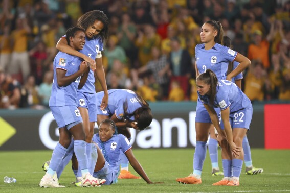 France players sit and stand on the pitch in dejection at the end of the Women's World Cup quarterfinal soccer match between Australia and France in Brisbane, Australia, Saturday, Aug. 12, 2023. (AP Photo/Tertius Pickard)