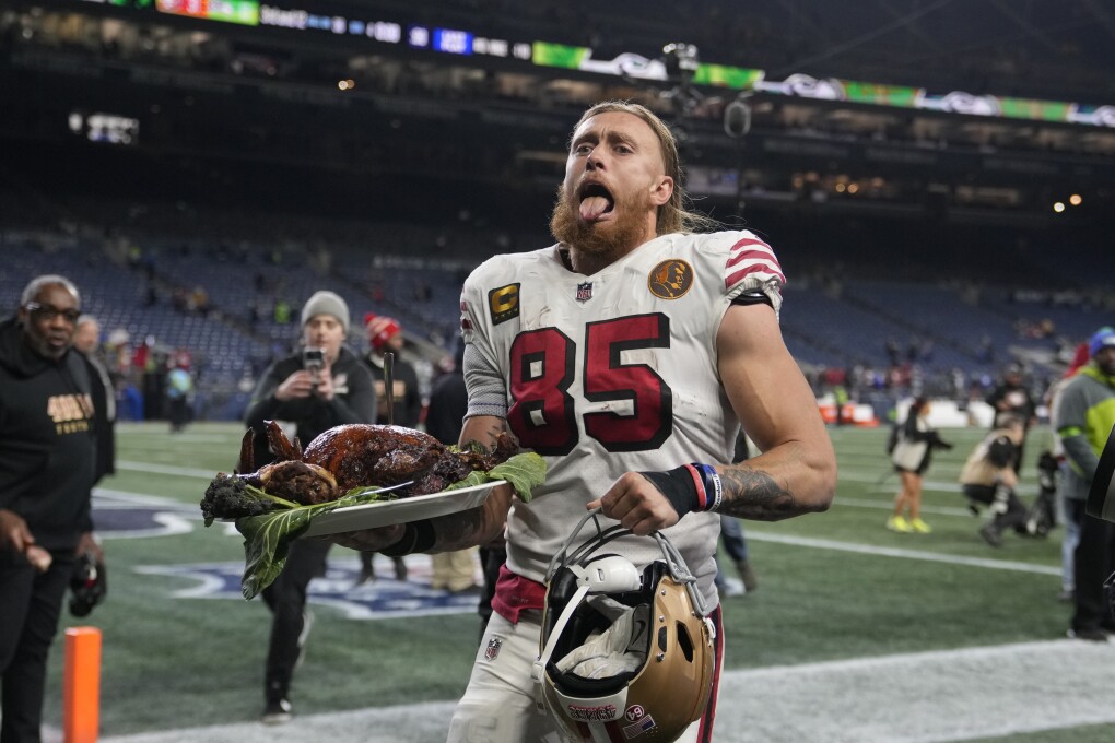 San Francisco 49ers tight end George Kittle carries a turkey after an NFL football game against the Seattle Seahawks, Thursday, Nov. 23, 2023, in Seattle. (AP Photo/Stephen Brashear)