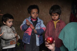 سه کودک آواره داخلی با تعجب به سیبی نگاه می کنند که مادرشان پس از گدایی به خانه آورده است، در اردوگاهی در حومه کابل، افغانستان، پنجشنبه، 2 فوریه 2023. از زمان اشغال آشفته کابل توسط طالبان در 15 اوت 2021، اقتصاد ویران شده از جنگ که زمانی تنها با کمک های بین المللی زنده نگه داشته می شد، اکنون در آستانه سقوط است.  (آپ عکس/ابراهیم نوروزی)