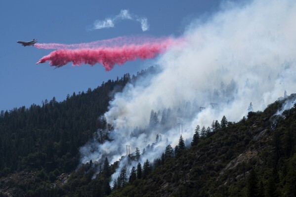 FILE - An air tanker drops fire retardant to battle the Dixie Fire in the Feather River Canyon in Plumas County, Calif., July 14, 2021. The Biden administration is trying to turn the tide on worsening wildfires in the U.S. West through a multi-billion dollar cleanup of forests choked with dead trees and undergrowth. (Paul Kitagaki Jr./The Sacramento Bee via AP)