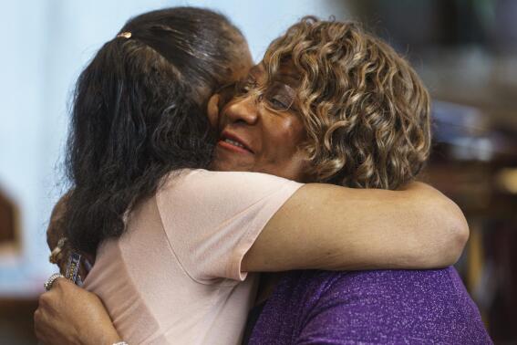 Pearl Taylor Devers, the chairperson for the Palm Springs Section 14 Survivors group, right, is hugged by another member at the United Methodist Church in Palm Springs, Calif., Sunday, April 16, 2023. Black and Latino Californians who were displaced from their Section 14 neighborhood in Palm Springs allege the city pushed them out by hiring contractors to destroy homes in an area that was tight-knit and full of diversity. (AP Photo/Damian Dovarganes)