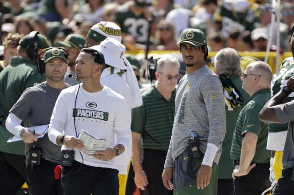 Injured Green Bay Packers quarterback Jordan Love looks on as head coach Matt LaFleur walks by during the first half of an NFL football game against the Indianapolis Colts Sunday, Sept. 15, 2024, in Green Bay, Wis. (AP Photo/Mike Roemer)