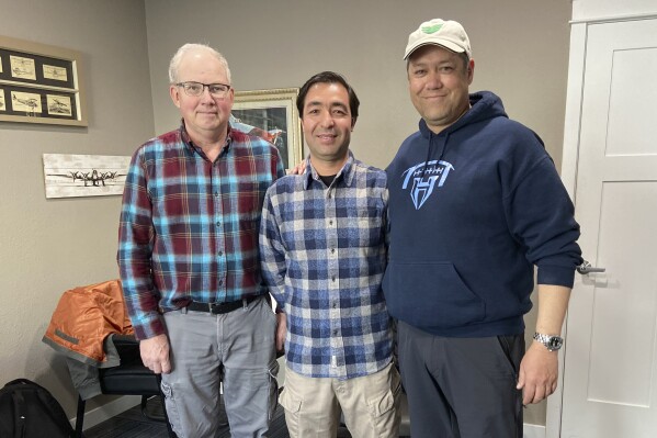 In this photo provided by Nikki Chung, Mohammad Hussain Musawi, center, stands with his flight instructor, left, and Darin Chung, co-founder of the Afghan American Development Group, a nonprofit that helps former Afghan military aviation personnel with refugee resettlement assistance in the U.S., at a flight hangar in Independence, Ore. on April 7, 2023. Musawi and two other Afghan Air Force pilots lost their lives when a small plane that he was piloting crashed near Independence on Dec. 16, 2023. (Nikki Chung via AP)