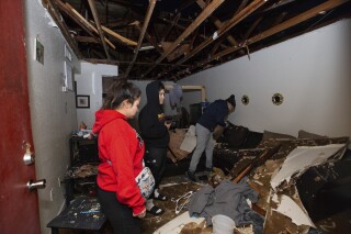 File - Jorge Amezquita, from right, cousin Adalene Castillo and girlfriend Cassandra Duarte look for a TV remote under debris after a tornado ripped the roof off the apartment on Jan. 24, 2023, at Beamer Place Apartments in Houston. When natural or manmade disasters happen, renters insurance can mean the difference between catastrophe and stability. (Yi-Chin Lee/Houston Chronicle via AP, File)