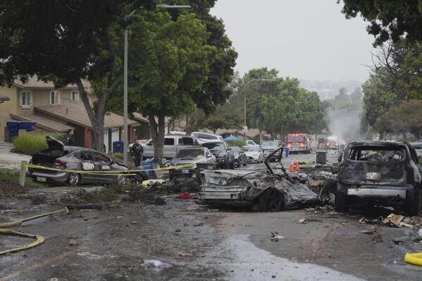 Authorities work the scene where a small plane crashed into a San Diego neighborhood, setting several homes on fire and forcing evacuations along several blocks early Thursday, May 22, 2025. (AP Photo/Gregory Bull)