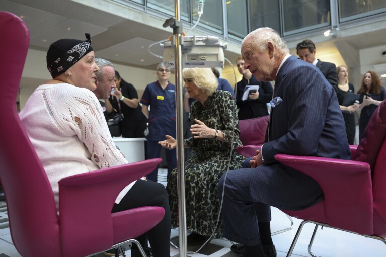 FILE - Britain's King Charles III and Queen Camilla meet with Lesley Woodbridge, patient receiving the second round of chemotherapy for sarcoma and her husband Roger Woodbridge during a visit to the University College Hospital Macmillan Cancer Centre in London, Tuesday April 30, 2024. King Charles III’s decision to be open about his cancer diagnosis has helped the new monarch connect with the people of Britain and strengthened the monarchy in the year since his dazzling coronation at Westminster Abbey. (Suzanne Plunkett, Pool Photo via AP, File)