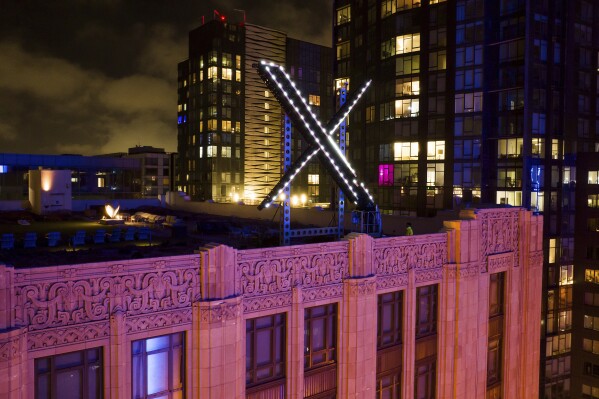File - Workers install lighting on an "X" sign atop the company headquarters, formerly known as Twitter, in San Francisco, on July 28, 2023. The social media platform X says it is trying to take action on a flood of posts sharing graphic media, violent speech and hateful conduct about the latest war between Israel and Hamas. (AP Photo/Noah Berger, File)