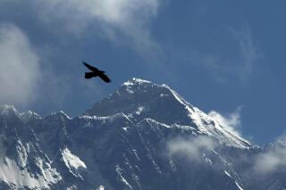 FILE - A bird flies with Mount Everest seen in the background from Namche Bajar, Solukhumbu district, Nepal, May 27, 2019. A Sherpa guide scaled Mount Everest on Sunday for the 26th time, matching the record set by a fellow Nepalese guide for the most ascents of the world’s highest peak. (AP Photo/Niranjan Shrestha, File)
