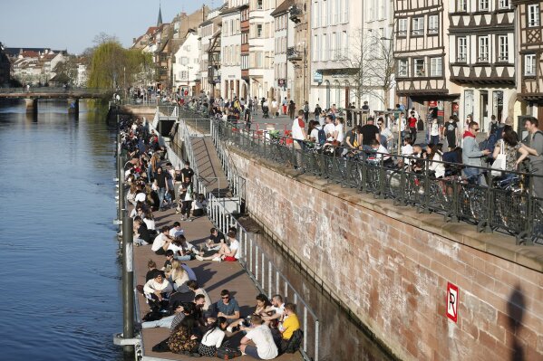 Youths gather along the Ill riverbanks in Strasbourg, eastern France, Wednesday, March 31, 2021. French President Emmanuel Macron is expected to impose new virus restrictions in a televised address to the nation Wednesday night, amid growing pressure to act more boldly to combat surging coronavirus hospitalizations. (AP Photo/Jean-Francois Badias)