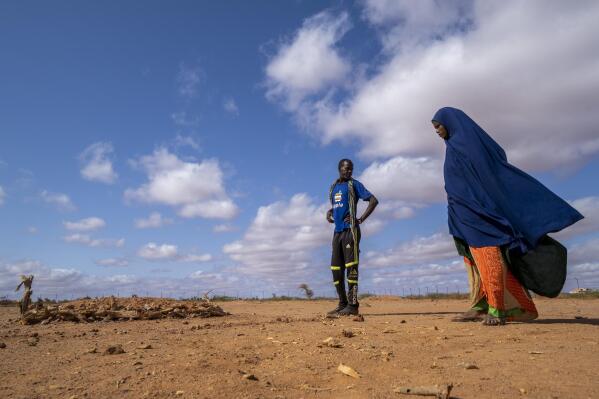 Fartum Issack, right, and her husband, Adan, stand by the grave of their 1-year-old daughter at a displacement camp on the outskirts of Dollow, Somalia, on Monday, Sept. 19, 2022. The graveyard opened in April, and there's easily room for hundreds more graves. (AP Photo/Jerome Delay)
