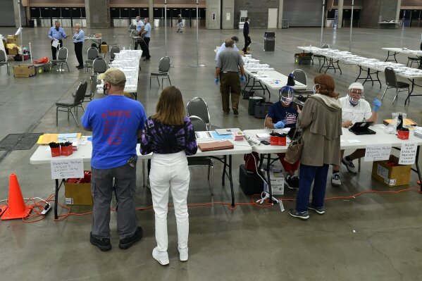 Voters register at their designated precinct to cast their ballot in the Kentucky primary at the Kentucky Exposition Center in Louisville, Ky., Tuesday, June 23, 2020. In an attempt to prevent the spread of the coronavirus, neighborhood precincts were closed and voters that didn't cast mail in ballots were directed to one central polling location. (AP Photo/Timothy D. Easley)