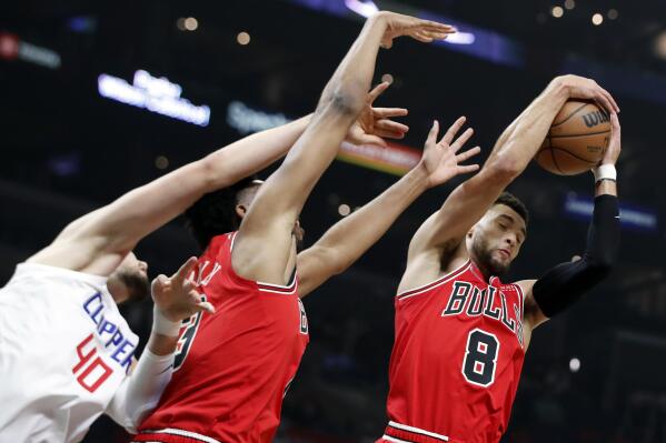 Chicago Bulls guard Zach LaVine, right, pulls down a rebound against Los Angeles Clippers center Ivica Zubac (40) and Bulls guard Devon Dotson, center, during the first half of an NBA basketball game Sunday, Nov. 14, 2021, in Los Angeles. (AP Photo/Alex Gallardo)