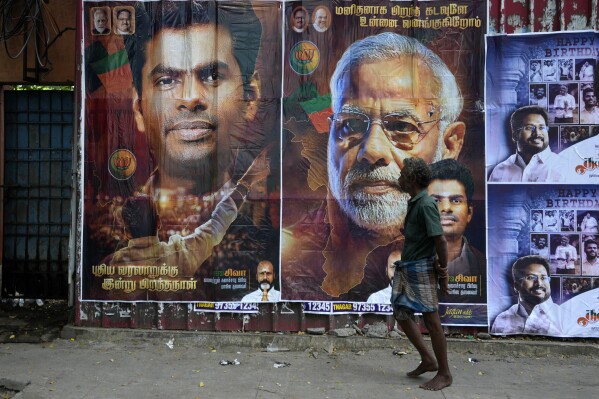 A man walks past posters with portraits of Indian Prime Minister Narendra Modi and Bharatiya Janata Party (BJP) state President K. Annamalai on a street in Chennai, India, Tuesday, June 4, 2024. (AP Photo/Mahesh Kumar A.)