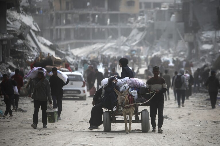 Palestinians carry their belongings after visiting their houses destroyed in the Israeli offensive on Khan Younis, Gaza Strip, Wednesday, March 6, 2024. (AP Photo/Mohammed Dahman)