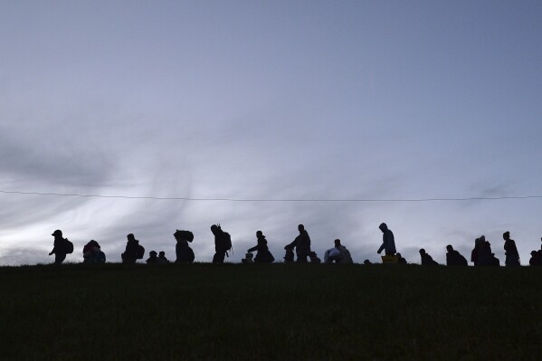 FILE - German federal police officers guide a group of migrants on their way after crossing the border between Austria and Germany in Wegscheid near Passau, Germany, on Oct. 28, 2015. Chancellor Olaf Scholz's cabinet on Wednesday Aug. 30, 2023 classified Moldova and Georgia as so-called “safe countries of origin” meaning asylum seekers from there can be rejected and deported faster than in the past. (AP Photo/Kerstin Joensson, File)